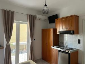 a small kitchen with wooden cabinets and a window at Riverside Rooms Ammoudia in Ammoudia