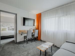 a room with a bed and a table with chairs at Mercure Annecy Sud in Annecy