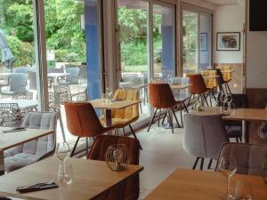 a restaurant with tables and chairs and windows at Mercure Brive in Ussac