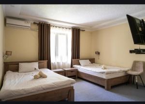 two beds in a hotel room with a teddy bear on them at Tem Hotel in Khorog
