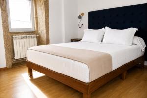 a bedroom with a large bed with a black headboard at Casa Cal da Rosins in Muxia