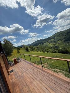 a deck with a bench and a view of the mountains at Dor de Munte in Vărtăneşti