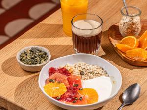 a table with a bowl of food and a glass of juice at Ibis Styles Saint Germain en Laye in Saint-Germain-en-Laye