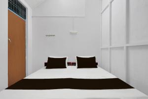 a bed in a white room with black pillows at SPOT ON Milan Hotel in Hāthras +22 photos