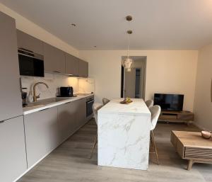 a kitchen with a white counter and a table at Marathi élégance T2 neuf avec SPA privatif in Biscarrosse