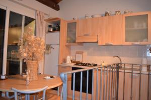 une cuisine avec des placards en bois et une table avec des chaises dans l'établissement Casa Med Holiday Home, à Isolabona