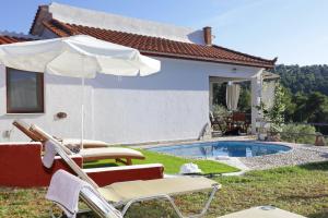 a pair of chairs and an umbrella next to a pool at VILLA VICTORIA in Ditropo