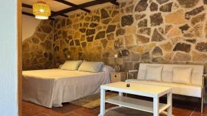 a room with two beds and a table and a stone wall at Alojamientos del Valle in Sotillo de la Adrada +32 photos