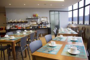 a restaurant with wooden tables and chairs and a kitchen at Pontual Hotel in Bocaiúva