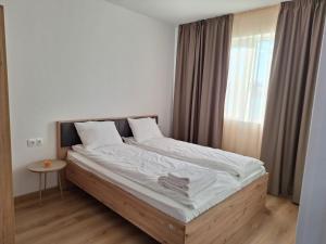 a bedroom with a large bed with white sheets and a window at Vila Nikalas in Tyulenovo