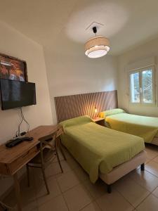 a bedroom with two beds and a desk and a television at Au bon clocher in Canari