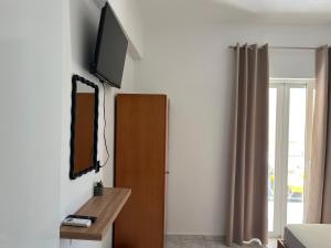 a room with a tv on the wall next to a door at Riverside Rooms Ammoudia in Ammoudia