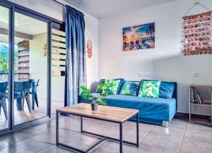 a living room with a blue couch and a table at Teahupo'o Lodge Tahiti - Maison familiale au cœur du village - Canoës inclus in Teahupoo