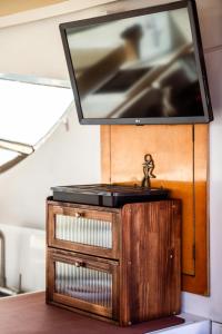 a flat screen tv on top of a wooden stand at BALI house boat in SantʼAntìoco