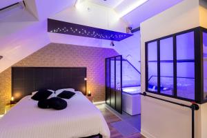 a bedroom with a large white bed with black pillows at L'Intemporel Éclipse Suite Spa Privatif in Champagne-sur-Oise