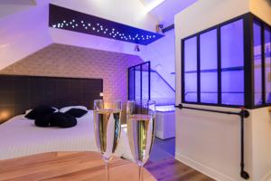 two champagne glasses sitting on a table in a bedroom at L'Intemporel Éclipse Suite Spa Privatif in Champagne-sur-Oise
