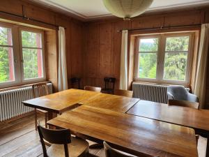 a dining room with a wooden table and two windows at Gasthaus Crestasee in Flims