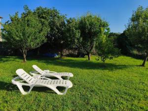 two white chairs sitting in the grass in a field at La Casuca de Marisa in Solórzano