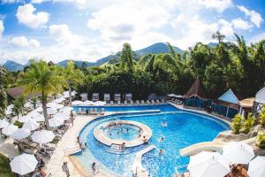 a pool at a resort with umbrellas and chairs at Hotel Magique Le Canton in Teresópolis