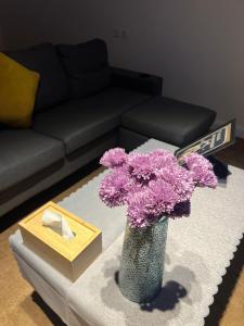 a vase with purple flowers on a table in a living room at شالية ريفي الفندقي هادي وسط المدينة in Az Zulfi