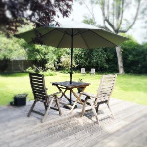a table and two chairs with an umbrella on a deck at River Cabin Retreat in Shepperton