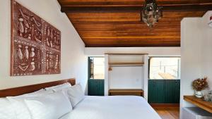 a bedroom with a white bed and wooden ceilings at Pousada Casa de Salim in Lençóis