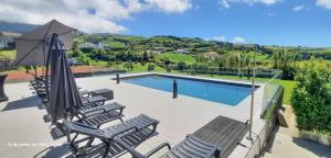 a patio with chairs and an umbrella and a swimming pool at Casa de Campo, Algarvia in Algarvia