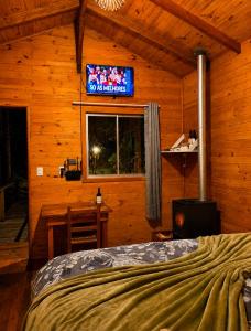 a bedroom with a bed and a tv on the wall at Cabana Recanto dos Aparados in Cambará