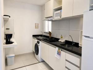 a kitchen with white cabinets and a washer and dryer at Hosts BR - Apartamentos funcionais in Fortaleza