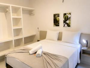 a white bedroom with two beds and shelves at Hosts BR - Apartamentos funcionais in Fortaleza +13 photos