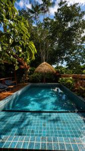 a swimming pool with a straw umbrella and trees at Vila da Mata in Alter do Chao