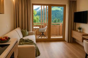 a living room with a couch and a large window at Aparthotel Iris - inklusive Wildschönau Premium Card in Auffach