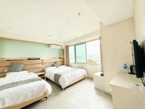 a hotel room with two beds and a flat screen tv at 枳兮酒店 渝中区解放碑 in Chongqing
