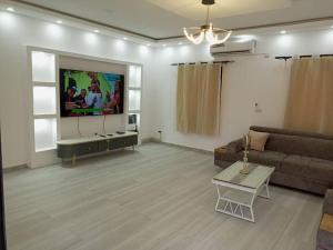 a living room with a couch and a flat screen tv at CarteSurTable - Votre havre de paix aux portes de la ville - Villa haut standing in Yamoussoukro