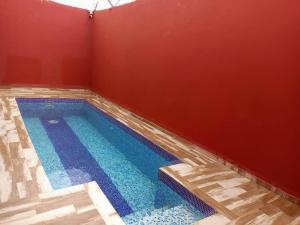 a swimming pool in a room with a red wall at CarteSurTable - Votre havre de paix aux portes de la ville - Villa haut standing in Yamoussoukro