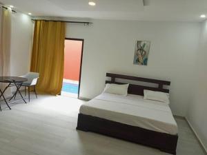 a bedroom with a bed and a table and a window at CarteSurTable - Votre havre de paix aux portes de la ville - Villa haut standing in Yamoussoukro