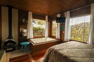 a bedroom with a bed and a bath tub with a window at Café e Cabanas Lenha no Fogo in Urubici