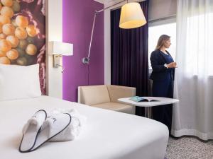 a woman standing in a hotel room looking out the window at Mercure Strasbourg Aéroport in Ostwald +138 photos