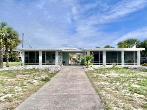 a large white house with a palm tree at Barefoot Beach Bungalow-Ground Level-3BR in St. George Island