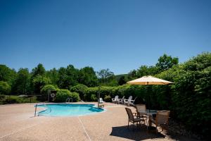 a patio with a table and chairs and an umbrella at Fireside Inn & Suites Gilford in Gilford