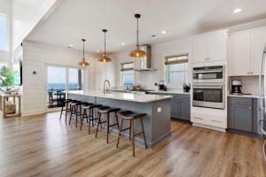 a kitchen with white cabinets and a island with bar stools at 8910 - Aquasition in Hatteras