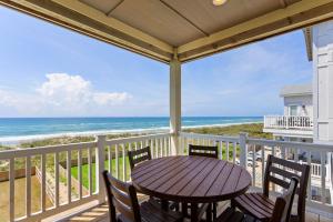 a porch with a table and chairs and the ocean at 8910 - Aquasition in Hatteras +80 photos