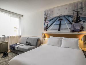 a hotel room with a bed and a chair at Novotel Paris Créteil Le Lac in Créteil +200 photos