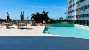 a swimming pool next to a building with tables and chairs at Beach Class Internacional Transamerica in Recife