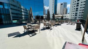 an outdoor patio with tables and chairs and umbrellas at Beach Class Internacional Transamerica in Recife