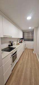 a kitchen with white cabinets and a wooden floor at Devesa Park in Playa de Gandia