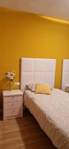 a bedroom with a white bed and a yellow wall at Devesa Park in Playa de Gandia