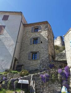 an old stone building with windows and purple flowers at Maison de village, Verdon in Trigance
