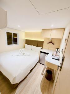 a bedroom with a large white bed and a desk at Le Hong Hotel Pratunam in Bangkok