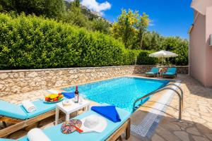 a pool with chairs and a table next to a house at Villa Situla in Barbati
